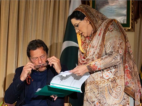 Pakistan government spokesperson Firdous Ashiq Awan consults with Pakistani Prime Minister Imran Khan in Islamabad, Pakistan, Monday, March 16, 2020. Khan said Monday he fears the new coronavirus will devastate developing nations' economies, and warned richer economies to prepare to write off the debts of the world's poorer countries.