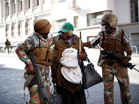 Soldiers of the South African National Defence Force (SANDF) escorts a homeless woman to a gathering point in the Johannesburg CBD, on March 27, 2020. South Africa came under a nationwide military-patrolled lockdown on March 27, 2020, joining other African countries imposing strict curfews and shutdowns in an attempt to halt the spread of the COVID-19 coronavirus across the continent.
