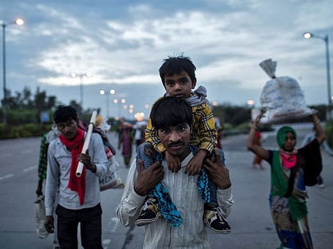 A migrant worker carries his son as they walk along a road with others to return to their village, during a 21-day nationwide lockdown to limit the spreading of coronavirus disease (COVID-19), in New Delhi on March 26, 2020.