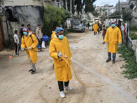 Palestinian volunteers wearing protective clothes and masks disinfect a street as a preventive measure against the spread of novel coronavirus, in Rafah in the southern Gaza Strip, on March 22, 2020. Authorities in Gaza today confirmed the first two cases of novel coronavirus, identifying them as Palestinians who had travelled to Pakistan and were being held in quarantine since their return.
The United Nations has warned that a COVID-19 outbreak in Gaza could be disastrous, given the high poverty rates and weak health system in the coastal strip under Israeli blockade since 2007. / AFP / SAID KHATIB