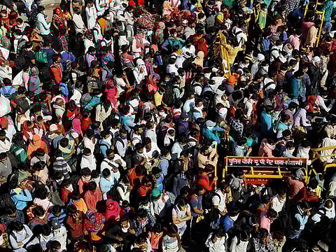 Migrant workers wait for buses along a highway with their families as they return to their villages, during a 21-day nationwide lockdown to limit the spreading of coronavirus disease (COVID-19), in Ghaziabad, on the outskirts of New Delhi, India
