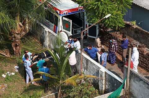People wearing protective masks carry the body of a man who died due to coronavirus disease (COVID-19), from an ambulance before his burial at a graveyard in Kochi, India, March 28.