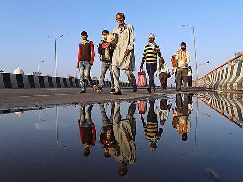 Migrant workers and their families walk along a road during a lockdown imposed due to the coronavirus.