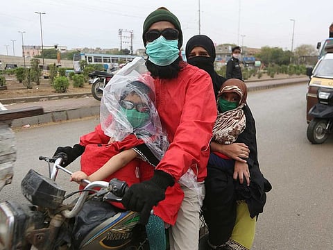 A family travels on a motorcycle wearing face masks during a government-imposed nationwide lockdown, as a preventive measure to contain the coronavirus, in Karachi, Pakistan, on March 26, 2020.
