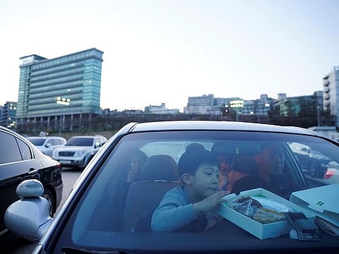 A boy looks at pies as people prepare to watch a movie from a car at a drive-in theatre that has been temporarily made for residents to enjoy movies while keeping social distancing following the outbreak of the coronavirus disease (COVID-19), in Seoul, South Korea March 27, 2020.