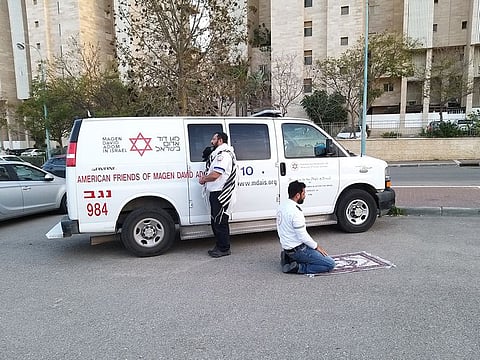 In an undated image provided by Magen David Adom, a pair of emergency medical technicians take a moment to pray in Beersheba, Israel. Avraham Mintz, 43, a Jew from Beersheba, wrapped himself in his prayer shawl and turned north toward Jerusalem. Zoher Abu Jama, 39, an Arab from nearby Rahat, unfolded his prayer rug and knelt facing south toward Mecca