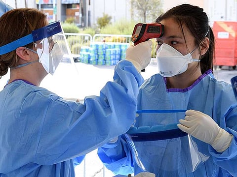 Touro University Nevada medical students get a no-touch forehead thermometer ready before conducting medical screenings at a temporary homeless shelter set up in a parking lot at Cashman Centre on March 28, 2020 in Las Vegas, Nevada.