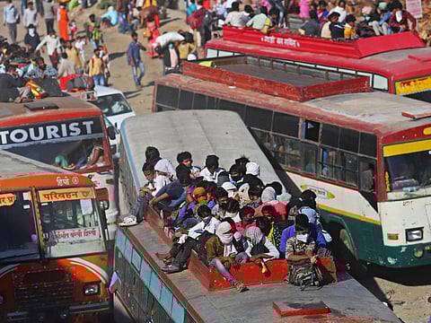 Migrant workers and their families sit atop a bus on the outskirts of Delhi during a lockdown imposed due to the coronavirus in Lalkuan, Uttarakhand, India, on March 29.