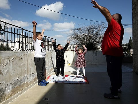 Palestinian father Victor Anton Sara, 41, exercises with his children Anton, 11, Elie, 6, and Silva, 5, while observing a partial lockdown to curb the spread of the coronavirus disease (COVID-19) at their home in Jerusalem March 25, 2020. Picture taken March 25, 2020. REUTERS/Ammar Awad