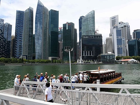 Visitors boarding a boat for a tour along the Singapore river in Singapore, as the city's financial district is seen in the background.