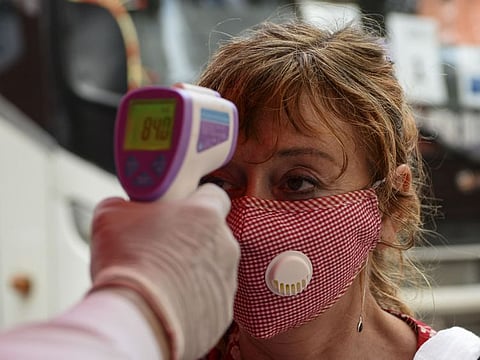 An embassy staff checks the body temperature of a French national being evacuated during India's government-imposed nationwide lockdown as a preventive measures against the spread of the COVID-19 coronavirus, at the Lycée Français International in New Delhi on March 30, 2020.
