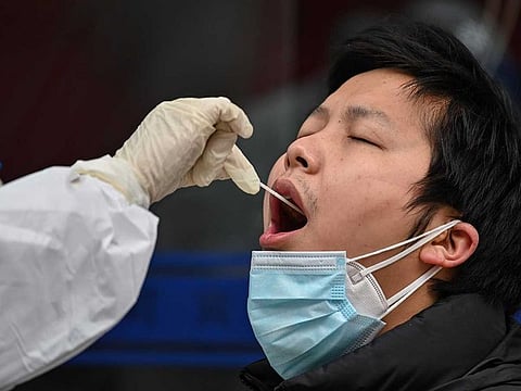 A medical worker takes a swab sample from a person to be tested for the COVID-19 novel coronavirus in Wuhan, China's central Hubei province on March 30, 2020. Wuhan, the central Chinese city where the coronavirus first emerged last year, partly reopened on March 28 after more than two months of near total isolation for its population of 11 million.