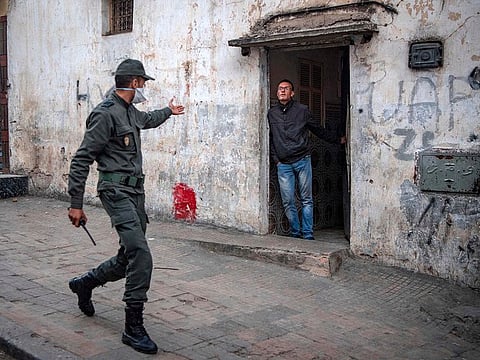 A member of Morocco's Interior Ministry Auxiliary Forces, patrolling as part of a larger combined security force, instructs a man to remain at home as a measure against the COVID-19 coronavirus pandemic in the capital Rabat's district of Takadoum on March 27, 2020