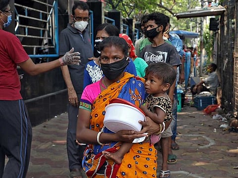 A homeless woman holding a child waits to receive food during a 21-day nationwide lockdown to slow the spreading of the coronavirus disease (COVID-19) in Kolkata, India, April 3, 2020.