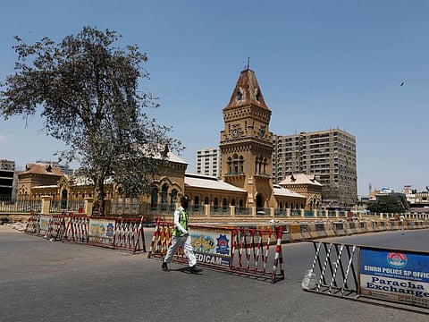 A traffic police officer walks past barriers used to block the road in front of the British era Empress Market building, during a lockdown after Pakistan shut all markets, public places and discouraged large gatherings amid an outbreak of coronavirus disease (COVID-19), in Karachi, April 3.