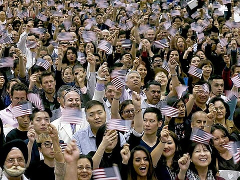 Newly christened Americans wave flags after taking the oath of US citizenship during a naturalisation ceremony at the Los Angeles Convention Centre.