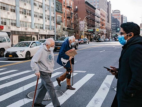 Pedestrians wearing face masks cross the street near Union Square in New York on March 27, 2020. White House advisers and public health officials are engaged in a fierce debate over recommending that all Americans wear masks when they leave their homes, with such a dramatic change in Americans' social behavior deeply dividing the Trump administration.