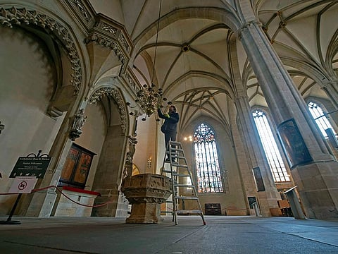 Matthias Schmitt fixes candles at a chandelier in the empty Cathedral of Mary (Mariendom), usually a popular tourist spot, in Erfurt, Germany, Tuesday, March 31, 2020. Normally the candlestick is usually lit at Easter, but services are currently prohibited. In order to slow down the spread of the coronavirus, the German government has considerably restricted public life and asked the citizens to stay at home. The new coronavirus causes mild or moderate symptoms for most people, but for some, especially older adults and people with existing health problems, it can cause more severe illness or death.