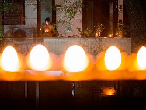 A woman turns on her mobile phone light in her balcony to observe a nine-minute vigil called by India's Prime Minister in a show of unity and solidarity in the fight against the coronavirus pandemic in New Delhi on April 5, 2020