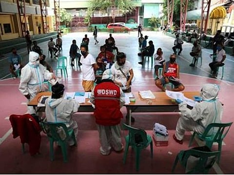 Personnel from the Philippines' Department of Social Welfare and Development (DSWD), wearing personal protective equipment, distribute the cash assistance under the Social Amelioration Program (SAP) to members of the Tricycle Operators’ and Drivers’ Association (TODA) Federation of Pasay City.