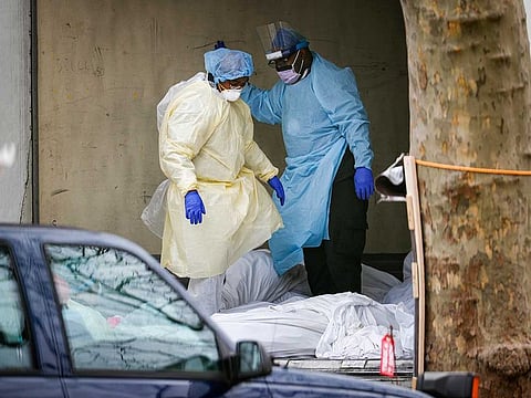 Medical workers step over bodies as they search a refrigerated trailer at Kingsbrook Jewish Medical Center, Friday, April 3, 2020, in the Brooklyn borough of New York.