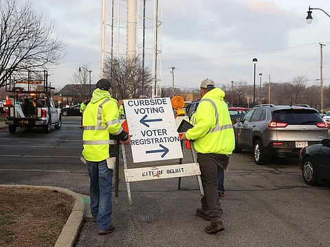 City workers carry a sign as a drive-up polling station is opened after the city of Beloit consolidated all their precincts in a single drive-up location outside City Hall to voters cast ballots from their vehicles during the presidential primary election held amid the coronavirus disease (COVID-19) outbreak in Beloit, Wisconsin, U.S. April 7, 2020.
