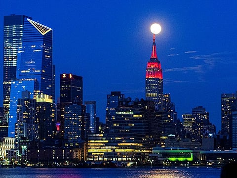 The Supermoon rises behind the Empire State Building while it glows red in solidarity with those infected with coronavirus as the outbreak of the disease (COVID-19) continues in the Manhattan borough of New York City, as it is seen from Hoboken, New Jersey, U.S., April 7, 2020.