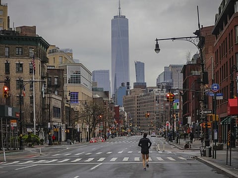 A lone jogger run on a partially empty 7th Avenue,  resulting from citywide restrictions calling for people to stay indoors and maintain social distancing in an effort to curb the spread of COVID-19 on March 28, in New York.