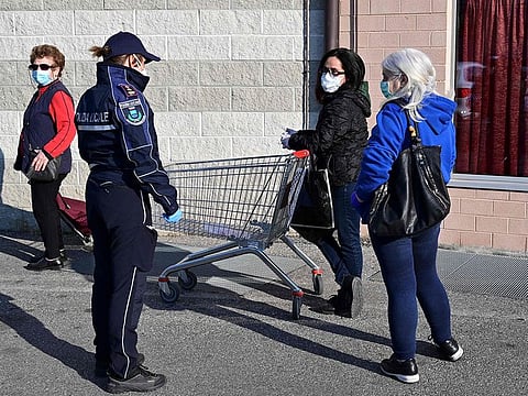 A police officer talks with women who queue outside a supermaket on April 7, 2020 in Canonica d'Adda, in Lombardy, where the mayor has implemented a measure specifying separate days when men and women will be allowed to go to supermarkets, in order to curb the spread of the novel coronavirus (COVID-19). The region of Lombardy, of which Milan is the capital, has been the hardest hit in Italy's coronavirus crisis, with more than 9,000 deaths.