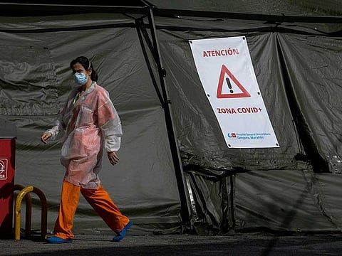 A healthcare worker walks past a sign reading "Attention, COVID Zone" attached to a big tent housing a field hospital outside the Gregorio Maranon Hospital in Madrid on April 8, 2020. Spain recorded today a second successive daily rise in coronavirus-related deaths with 757 fatalities, lifting the total toll in Europe's second-hardest-hit country after Italy by 5.5 percent to 14,555.