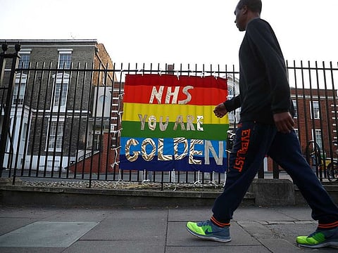 A man walks past an NHS sign outside King's College Hospital, as the spread of the coronavirus disease (COVID-19) continues, in London, Britain April 9, 2020.
