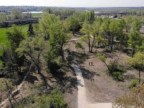 A photo taken on April 9, 2020 and handout on April 10, 2020 by the Treviolo municipal police shows an aerial image taken by a DJI Mavic 2 Enterprise drone equipped with a thermal sensor, with a scene featuring a police officer and its instructor (Bottom C) taken with a regular sensor, in Treviolo, Lombardy, during the country's lockdown aimed at stopping the spread of the COVID-19 pandemic, caused by the novel coronavirus. A seeing eye attached to its top hides a heat sensor that gives the offender's temperature to an officer operating the bread-loaf-length machine with a remote. The thermal map on his hand-held screen resembles a psychodelic video, bright orange and purple blobs instead of faces and trees shining in florescent yellow.