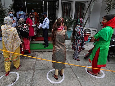 Indians queue up outside a bank to withdraw money during lockdown in Jammu, India, Tuesday, April 7, 2020.