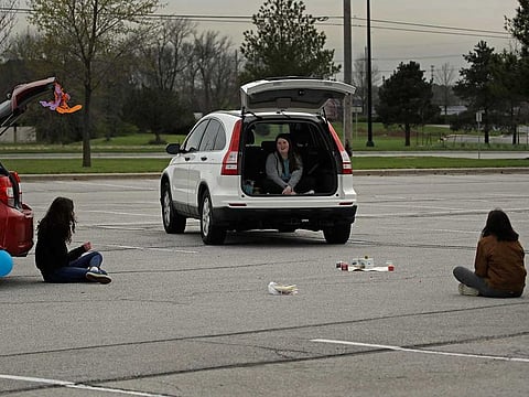 Friends Paige Snider, Maeve MacNaughton, and Maya Wood gather while keeping their distance to celebrate Snider's belated birthday in a high school parking lot on April 10, 2020, in Olathe, Kansas, US.