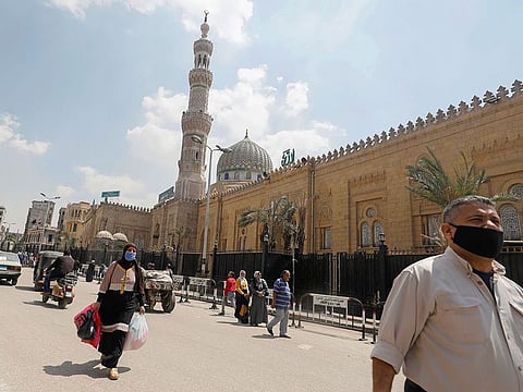 People wear protective face masks amid concerns over the coronavirus disease (COVID-19) walk in front of the closed El Sayeda Zainab Mosque near markets that sell traditional Ramadan lanterns, in Cairo