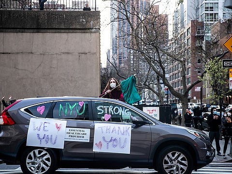 A woman holds a flag to thank medical workers outside NYU Langone Hospital during the outbreak of the coronavirus disease (COVID-19) in the Manhattan borough of New York City.