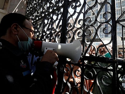 A police officer uses a megaphone, requesting people to go and pray at home, at the locked entrance gate of a mosque during a lockdown after Pakistan shut all markets, public places and discouraged large gatherings amid an outbreak of coronavirus disease, in Karachi.