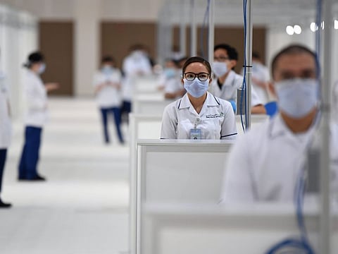 Hospital staff pose for a picture at a huge field hospital being built by the government of Dubai in the United Arab Emirates, on April 14, 2020, with a capacity of more than 3000 patients at the Dubai international Convention and Exhibition Center amid the COVID-19 pandemic. / AFP / KARIM SAHIB