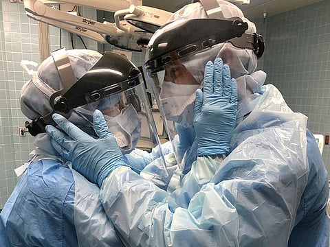 Nurses Mindy Brock and Ben Cayer, wearing protective equipment, hold each other and look into each other's eyes, in Tampa General Hospital in Tampa, Florida