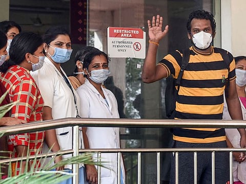 Taxi driver Latheesh waves as he leaves after being discharged from a hospital following his recovery from COVID-19, in Kochi on April 9.