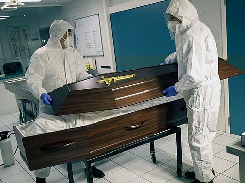 Workers, wearing a full protective equipment, close the casket of someone who has died of coronavirus at the Fontaine funeral home in Charleroi, Belgium, on Wednesday.