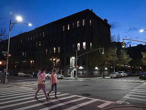 People wearing masks cross the street at Langston Hughes Place in New York.