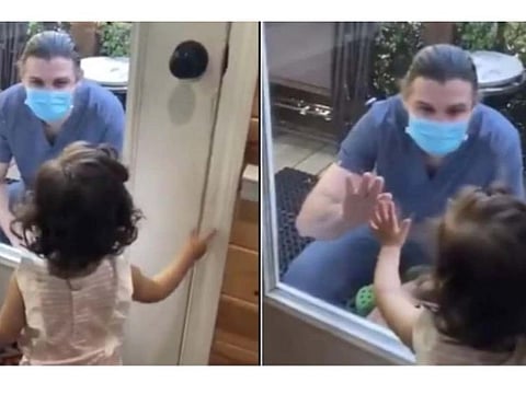 Doctor meets baby girl from behind glass door
