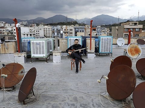Composer and musician Midya Farajnejad plays the tar on the roof of his home in Tehran Iran.