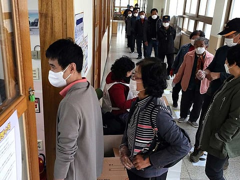 People wearing face masks to help protect against the spread of the new coronavirus wait in line to cast their votes for the parliamentary elections at a polling station in Nonsan, South Korea, Wednesday, April 15, 2020.