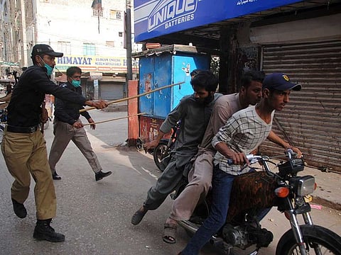 Police officers try to restrict people from defying the nation-wide lockdown to curb the spread of the coronavirus, in Hyderabad, Pakistan, Monday, April 13, 2020.