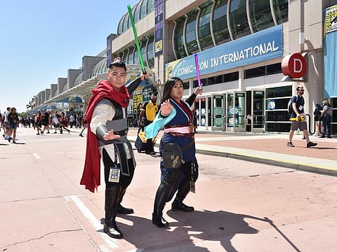 In this file photo taken on July 19, 2019 Cosplayers walk by the Convention Center during Comic Con in San Diego, California.