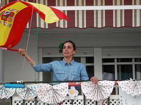 A woman waves a Spanish flag after applauding in support of health workers, during lockdown amid the coronavirus disease (COVID-19) outbreak, in Ronda, southern Spain, April 18, 2020.