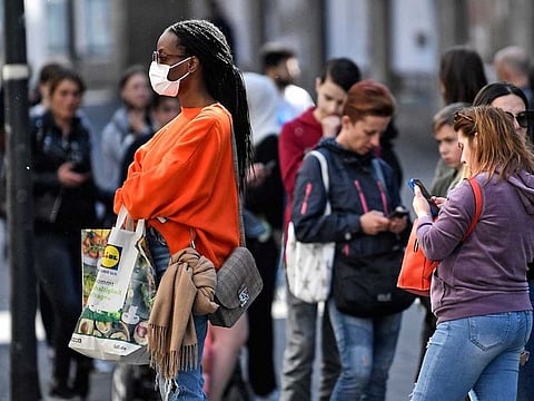 People waiting with social distance in front of a shop as many smaller stores are allowed to open in Essen, Germany, Monday, April 20, 2020. Europe's biggest economy, starts reopening some of its stores and factories after weeks of lockdown due to the new coronavirus outbreak.