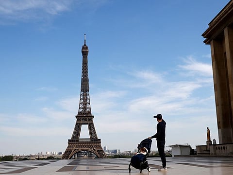 A man takes a picture of the Eiffel Tower on an empty esplanade in Paris amid a strict lockdown in France aimed at curbing the spread of the COVID-19 pandemic